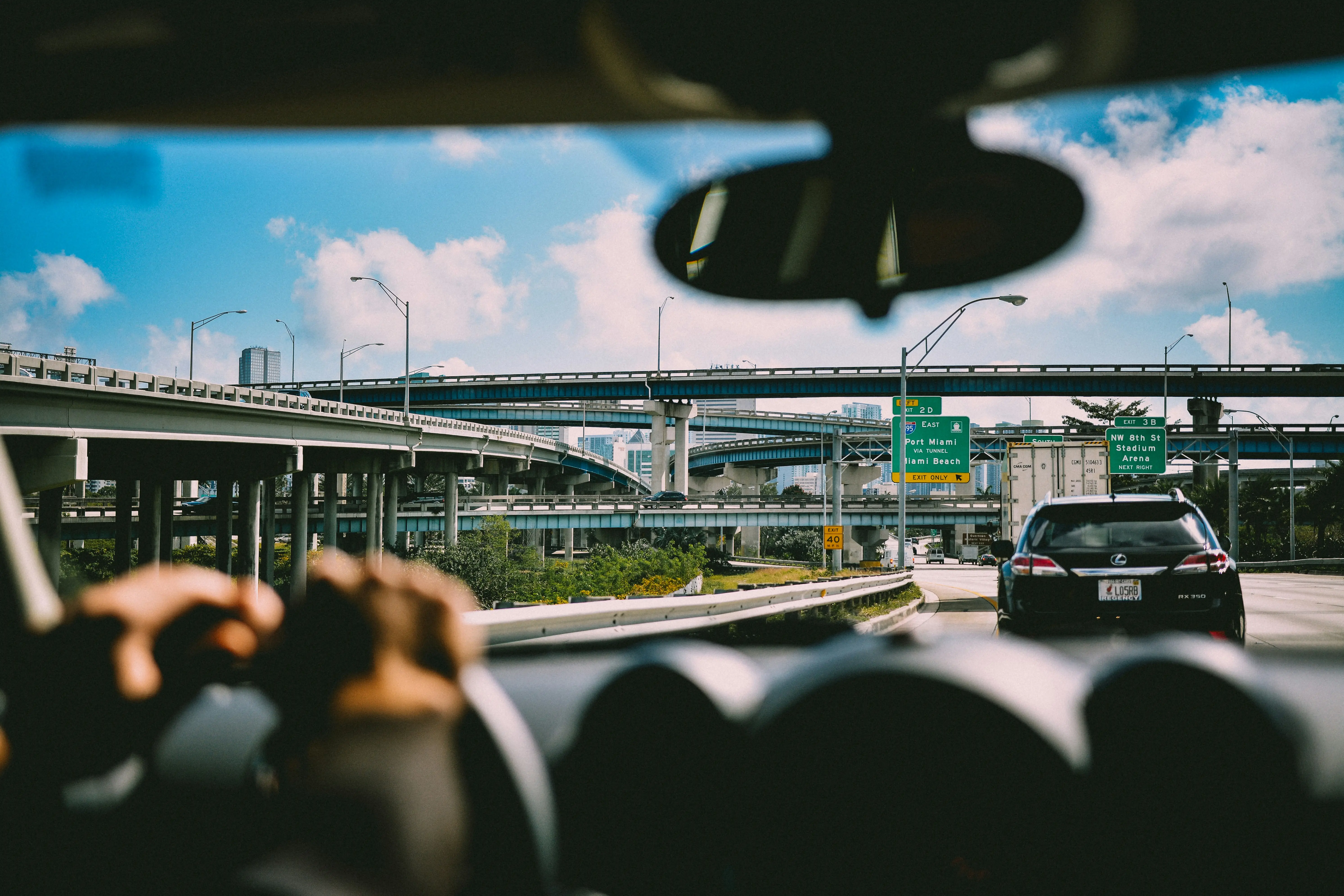 View from a driver's seat on a Florida highway, with overpasses and directional signs ahead.